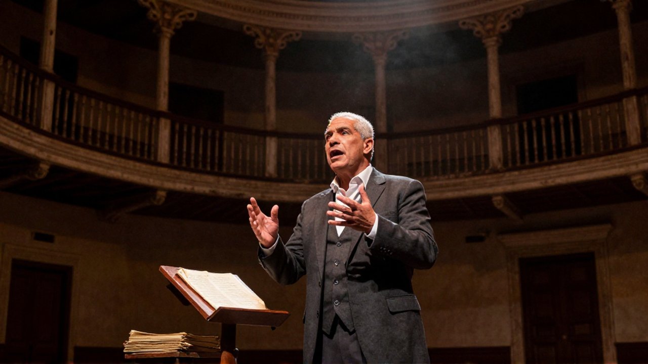 A passionate actor performs a dramatic monologue on a dimly lit, historic theater stage.